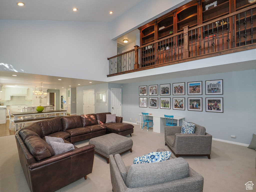 Carpeted living room featuring an inviting chandelier and a towering ceiling