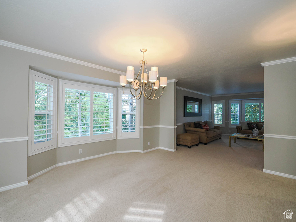 Unfurnished room with light carpet, a notable chandelier, and crown molding