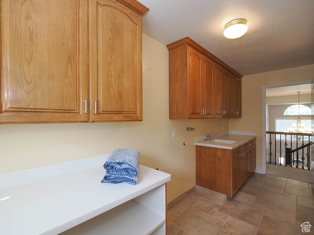 Laundry area with an inviting chandelier, sink, cabinets, and washer hookup