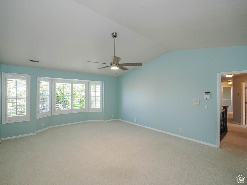 Unfurnished room featuring ceiling fan, vaulted ceiling, and light carpet