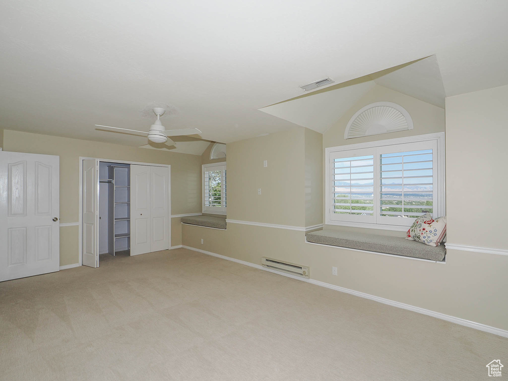 Unfurnished bedroom with ceiling fan, a baseboard heating unit, vaulted ceiling, light colored carpet, and a closet