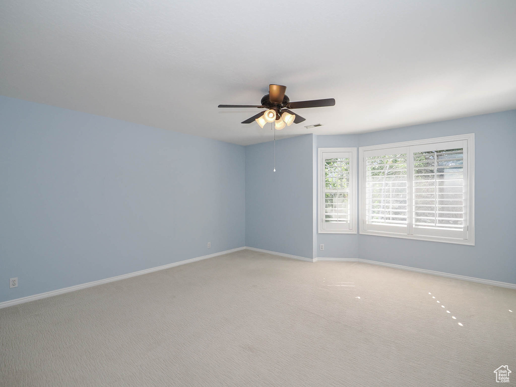 Carpeted spare room featuring ceiling fan
