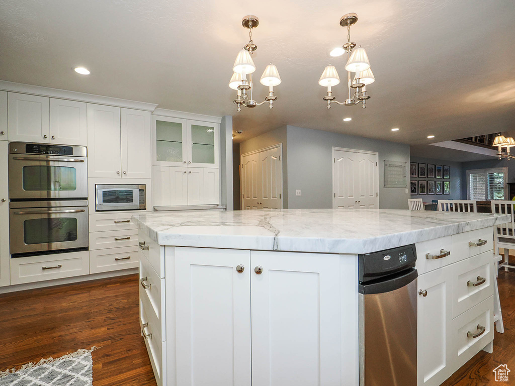 Kitchen featuring a kitchen island, dark hardwood / wood-style floors, pendant lighting, white cabinetry, and stainless steel appliances