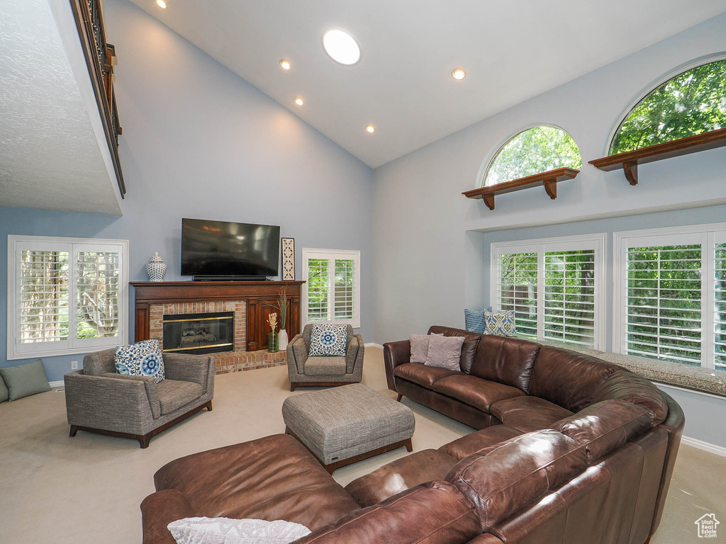 Living room featuring high vaulted ceiling, a fireplace, and light colored carpet