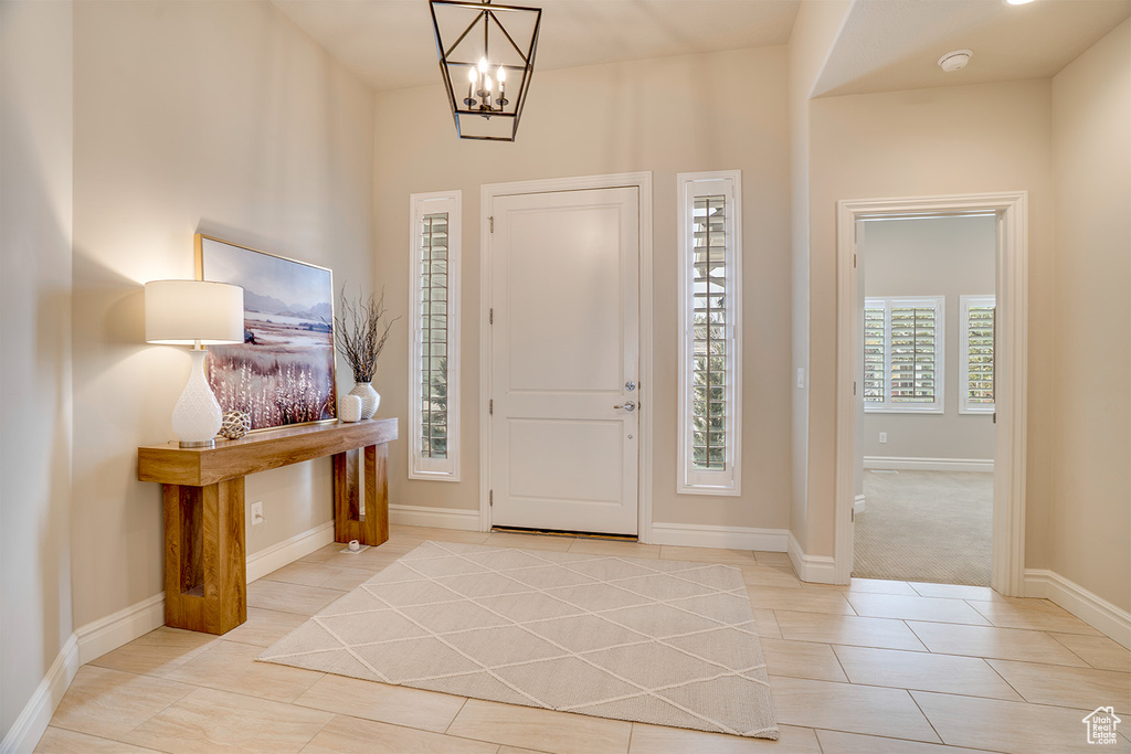 Foyer with baseboards, a notable chandelier, and light tile patterned floors