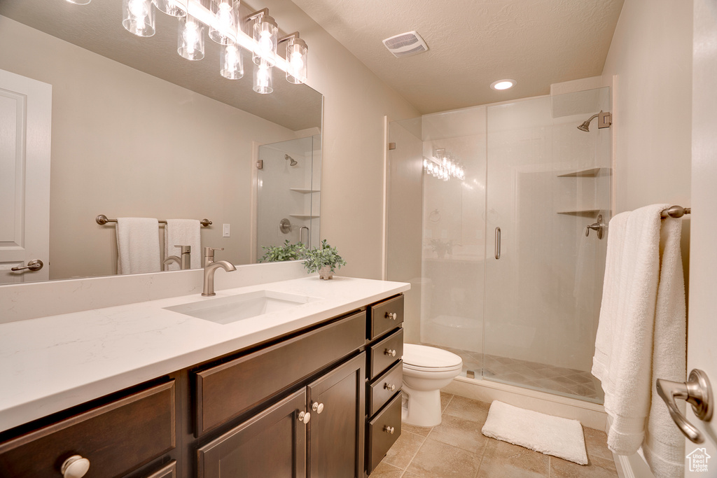 Full bath with tile patterned flooring, visible vents, toilet, vanity, and a stall shower