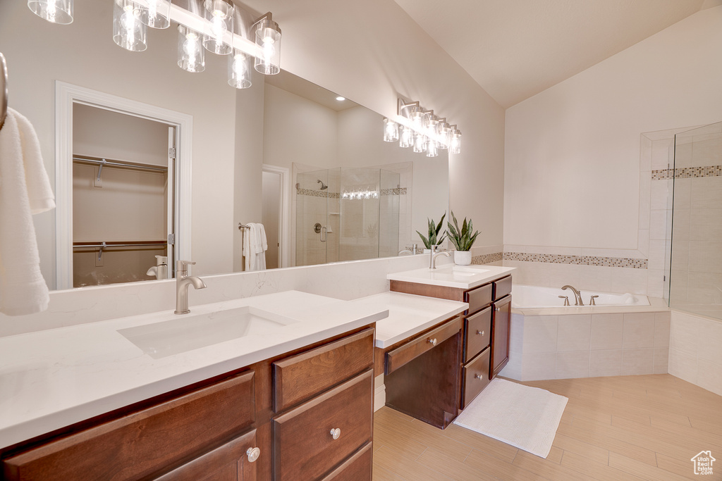 Bathroom with a shower stall, a spacious closet, vaulted ceiling, vanity, and a bath