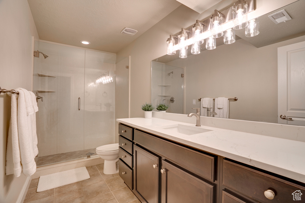 Full bathroom featuring a shower stall, vanity, toilet, tile patterned flooring, and visible vents