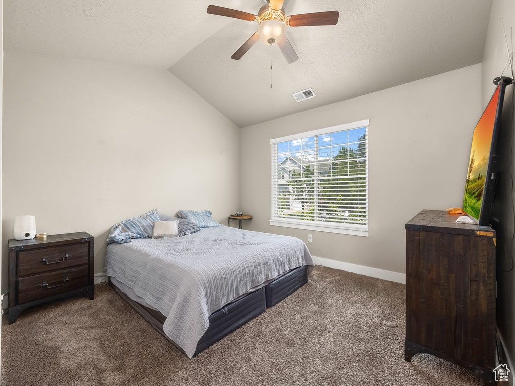 Carpeted bedroom with ceiling fan and vaulted ceiling