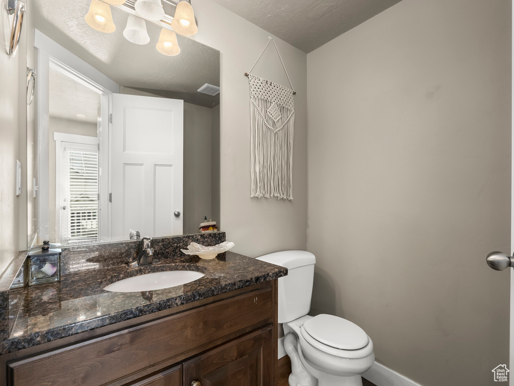 Bathroom featuring a textured ceiling, toilet, and vanity