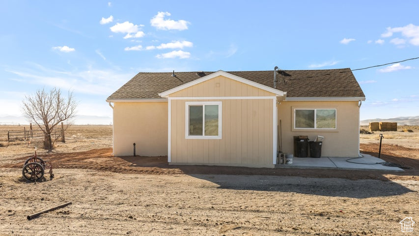 Back of house featuring roof with shingles and a patio