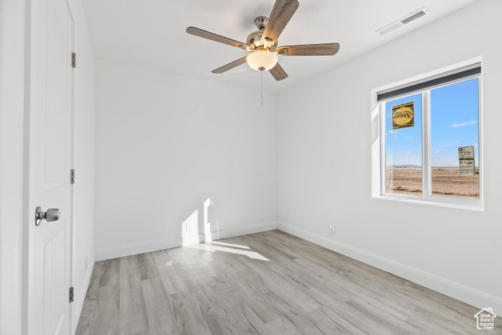 Unfurnished room with ceiling fan, wood finished floors, and baseboards