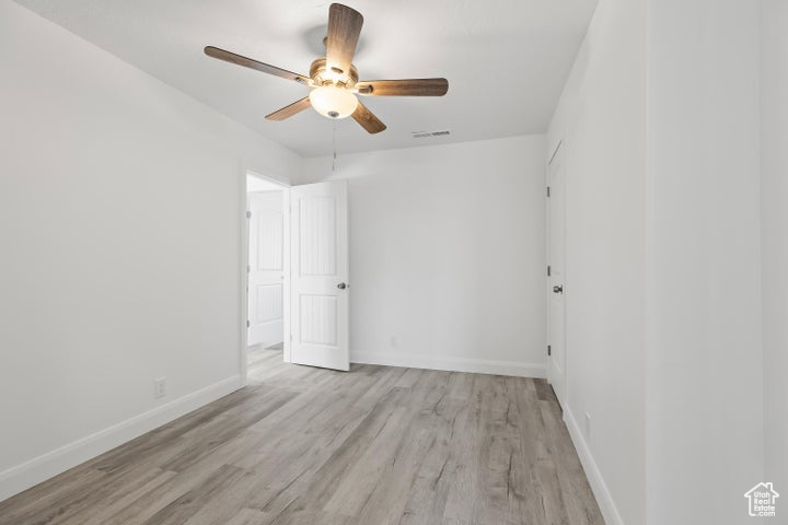 Spare room featuring wood finished floors, ceiling fan, and baseboards