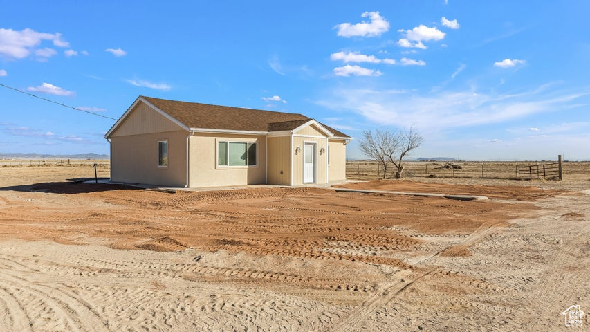 View of front of house with an outbuilding, fence, and a rural view