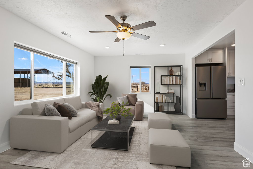 Living area with wood finished floors, baseboards, plenty of natural light, recessed lighting, and a textured ceiling