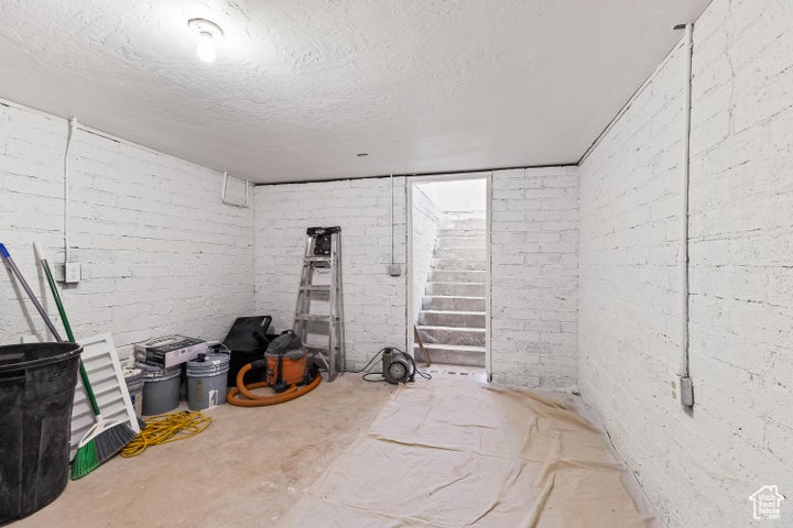 Finished below grade area featuring a textured ceiling and stairway