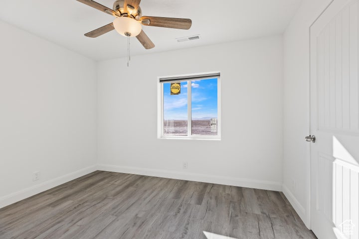 Spare room with wood finished floors, ceiling fan, and baseboards