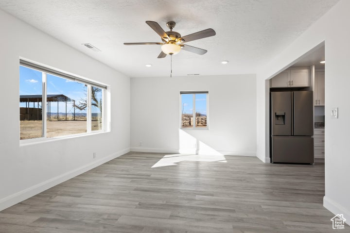 Spare room featuring healthy amount of natural light, ceiling fan, baseboards, light wood-type flooring, and recessed lighting