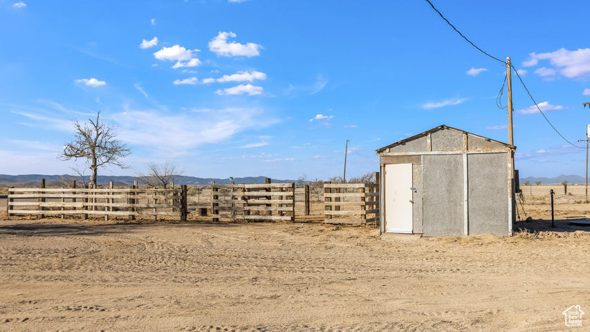 View of yard featuring fence, a storage shed, a view of rural / pastoral area, and an outbuilding
