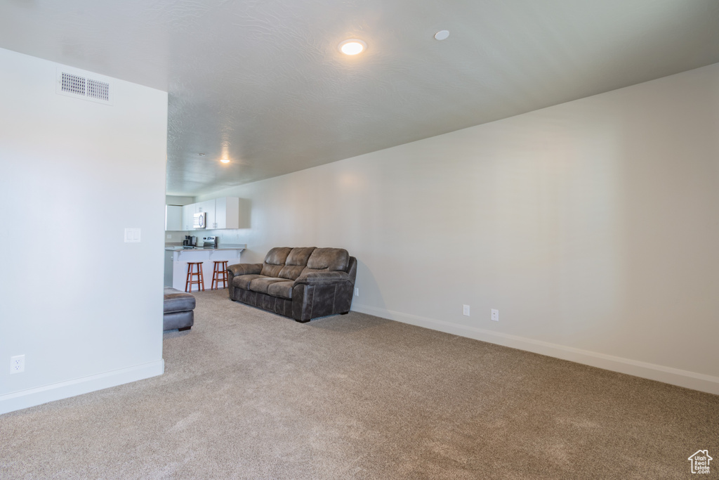 Living area featuring light colored carpet and baseboards