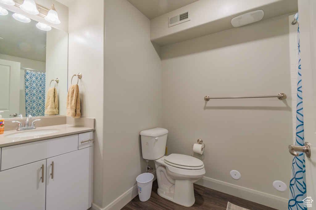 Full bathroom featuring wood finished floors, vanity, toilet, and baseboards