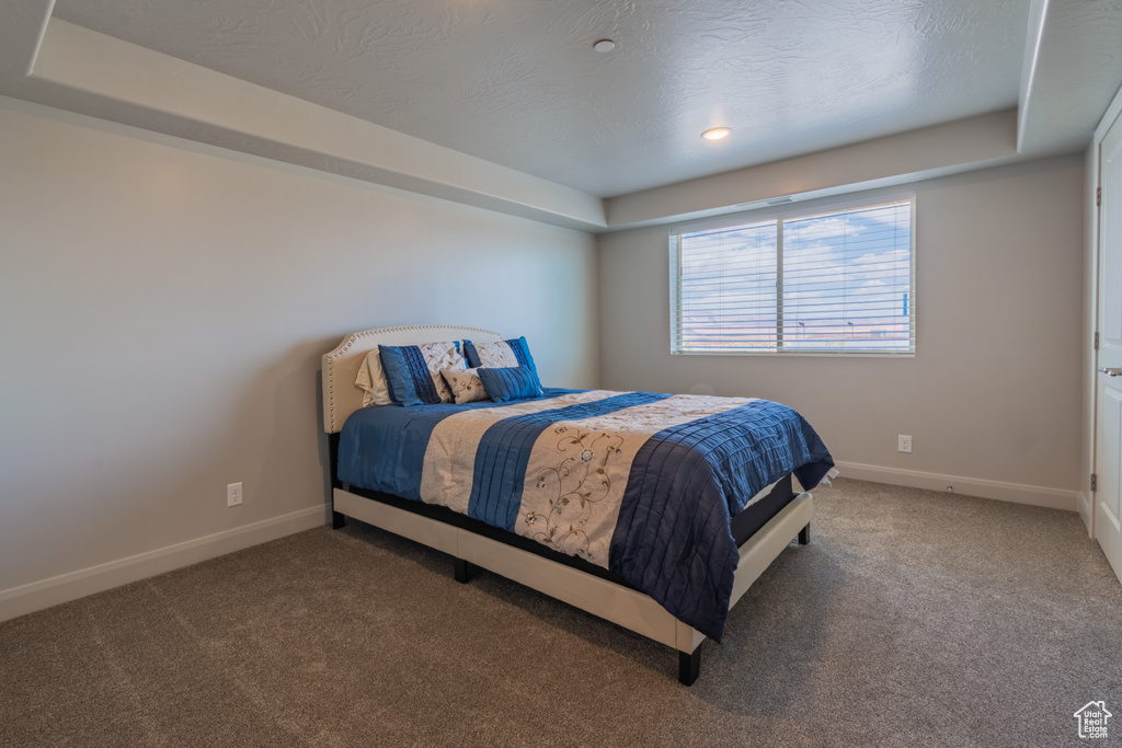 Bedroom with carpet floors, baseboards, and a textured ceiling