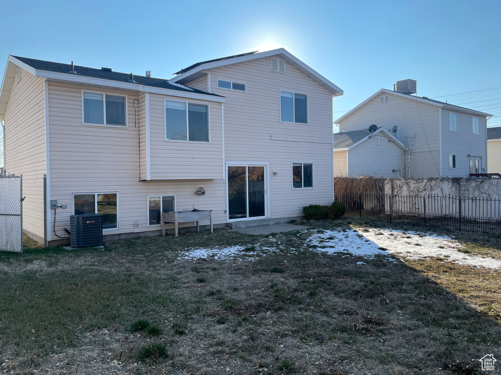 Rear view of house featuring central AC and a lawn