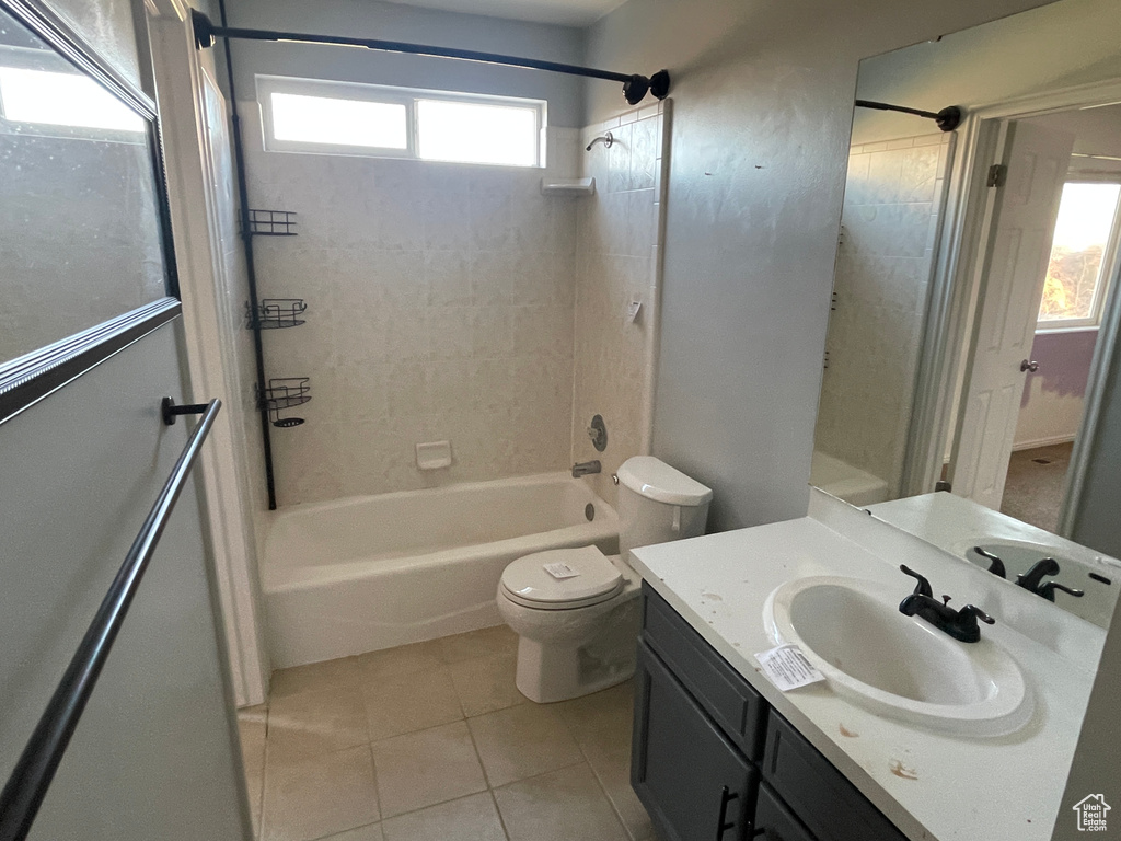 Full bathroom with tiled shower / bath, toilet, tile patterned floors, and vanity