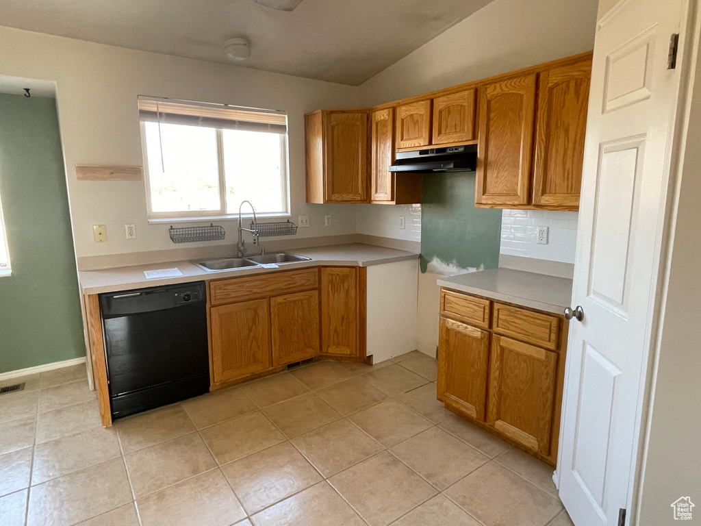 Kitchen featuring light tile patterned flooring, dishwasher, lofted ceiling, sink, and backsplash