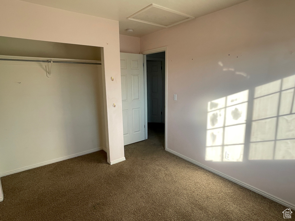 Unfurnished bedroom with dark carpet and a closet