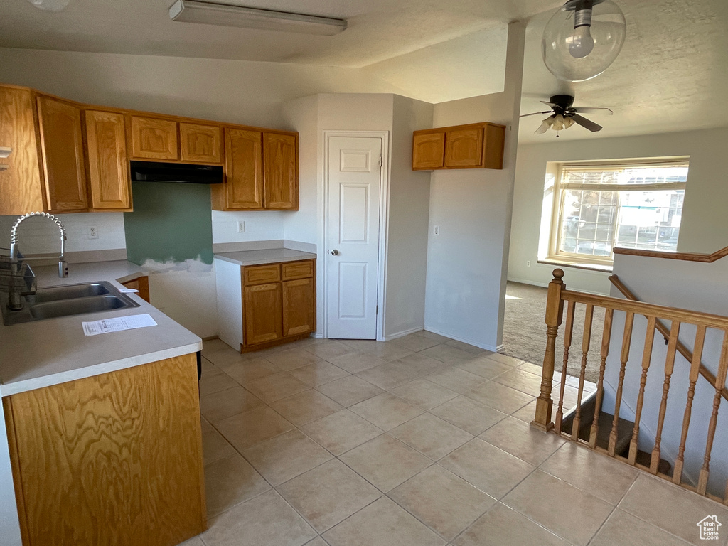 Kitchen featuring vaulted ceiling, sink, light tile patterned floors, and ceiling fan
