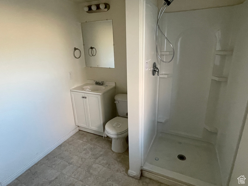 Bathroom featuring walk in shower, vanity, and toilet