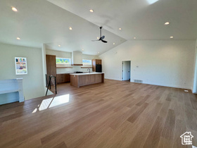 Unfurnished living room featuring ceiling fan, lofted ceiling, and light wood-type flooring