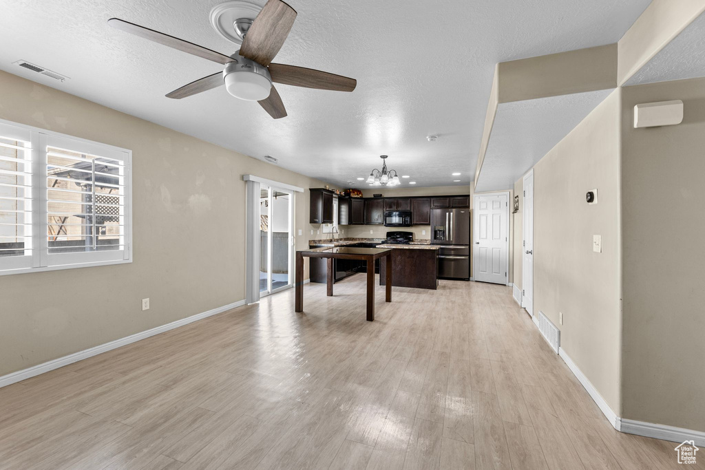 Game room with ceiling fan with notable chandelier, light hardwood / wood-style floors, and a textured ceiling