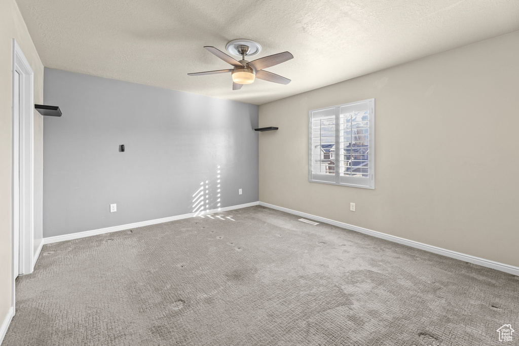 Carpeted spare room with a textured ceiling and ceiling fan