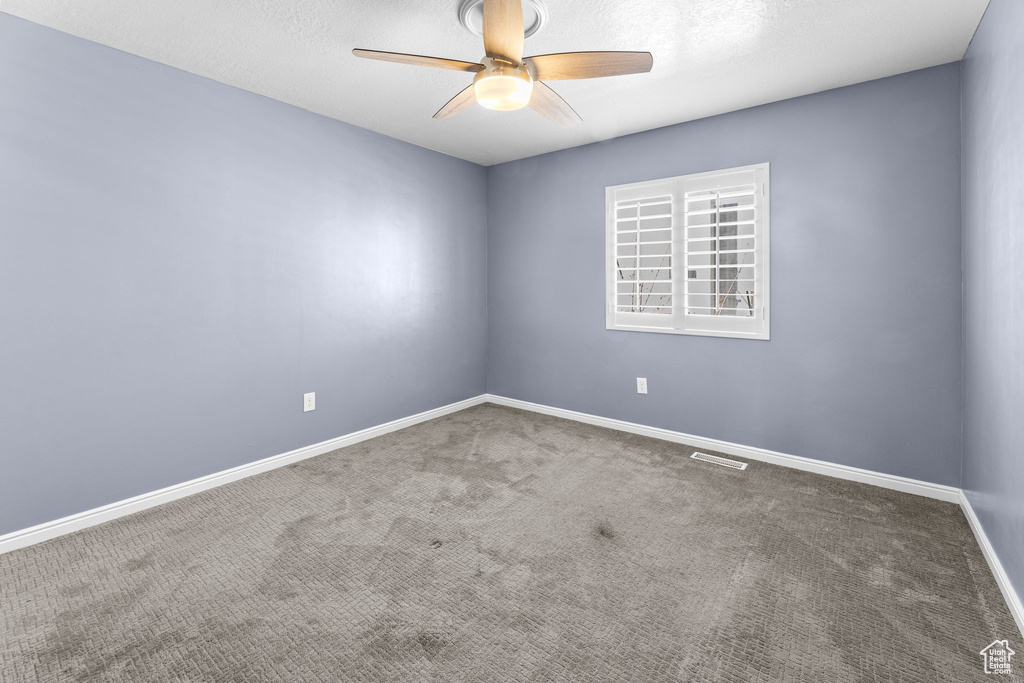 Carpeted spare room with a textured ceiling and ceiling fan