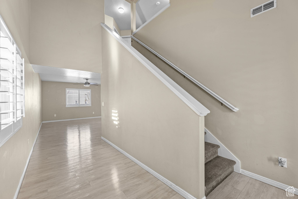 Staircase featuring hardwood / wood-style floors, a towering ceiling, and ceiling fan