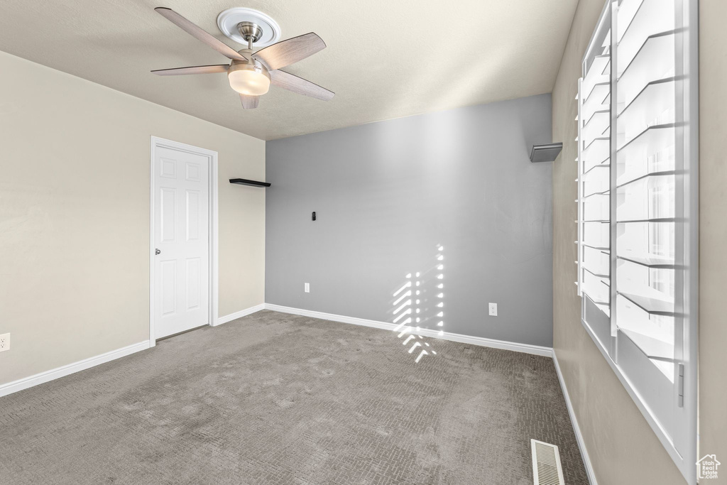 Carpeted spare room with ceiling fan and plenty of natural light