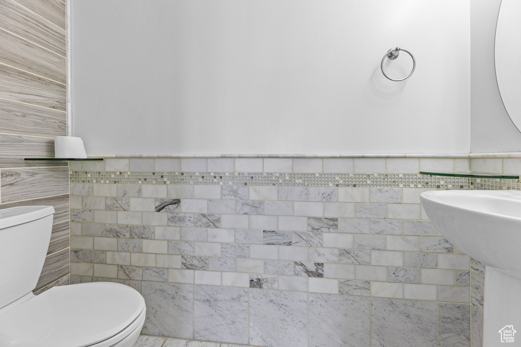 Bathroom featuring tile walls and toilet