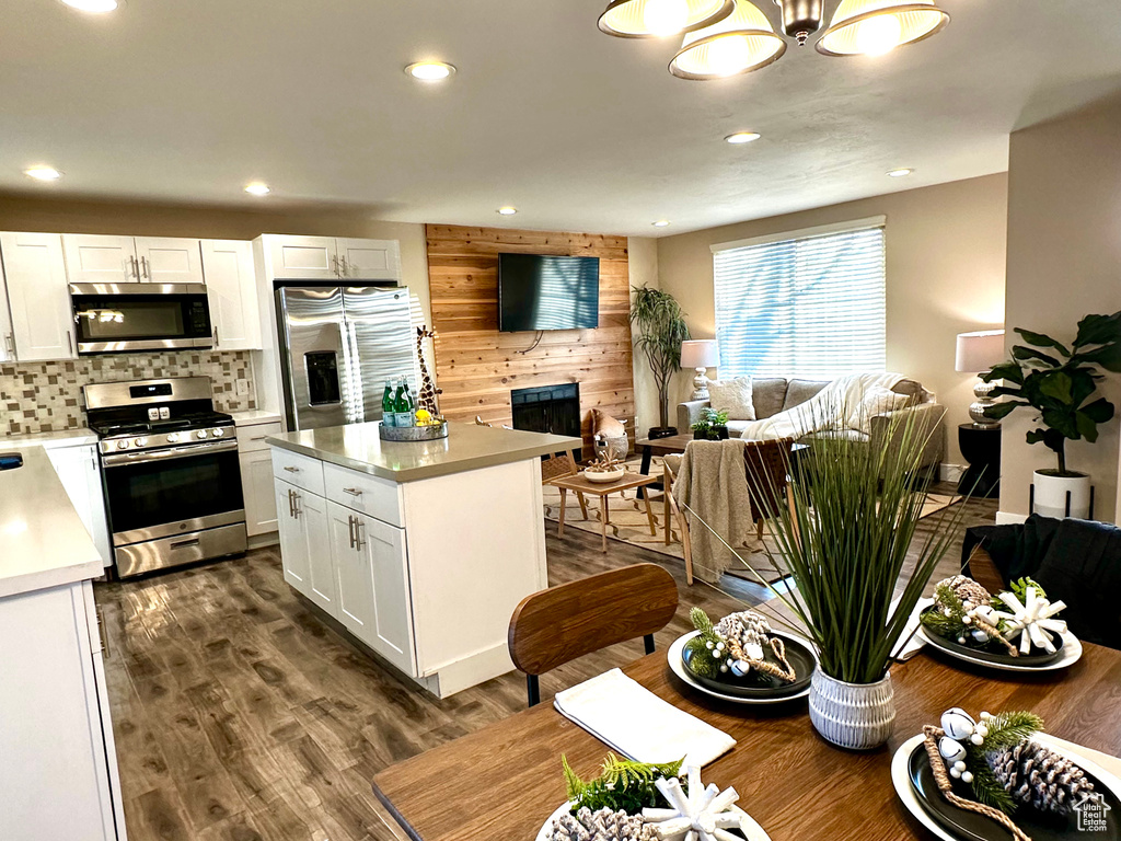 Kitchen with tasteful backsplash, dark hardwood / wood-style floors, a kitchen island, stainless steel appliances, and white cabinets