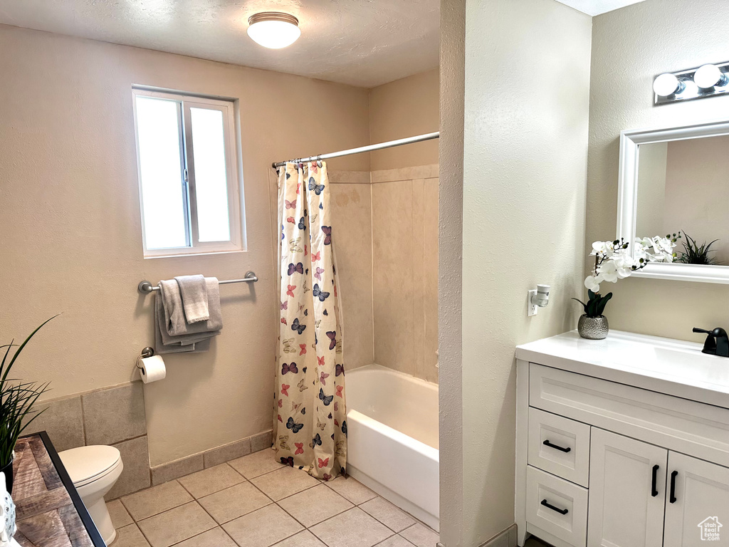 Bathroom with shower / tub combo with curtain, toilet, vanity, tile patterned flooring, and baseboards