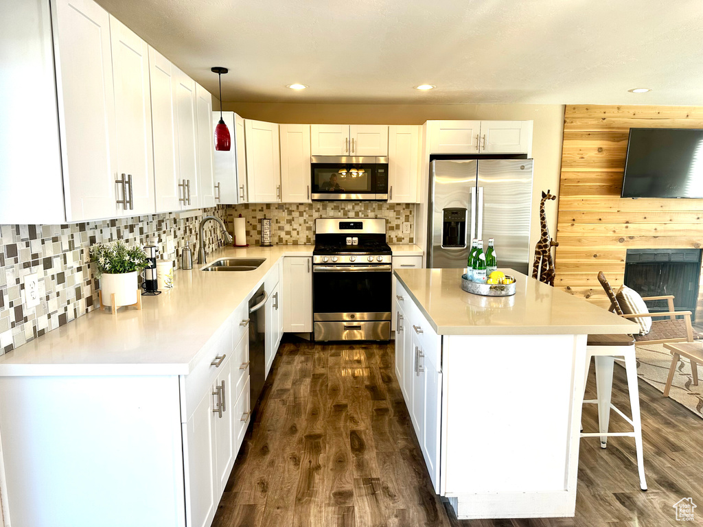 Kitchen with stainless steel appliances, sink, pendant lighting, and white cabinets