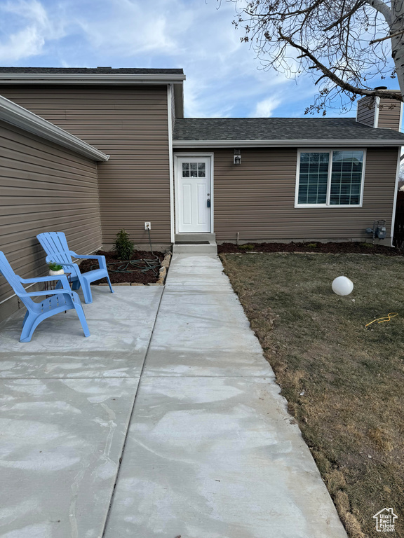 Property entrance with a patio area and a lawn