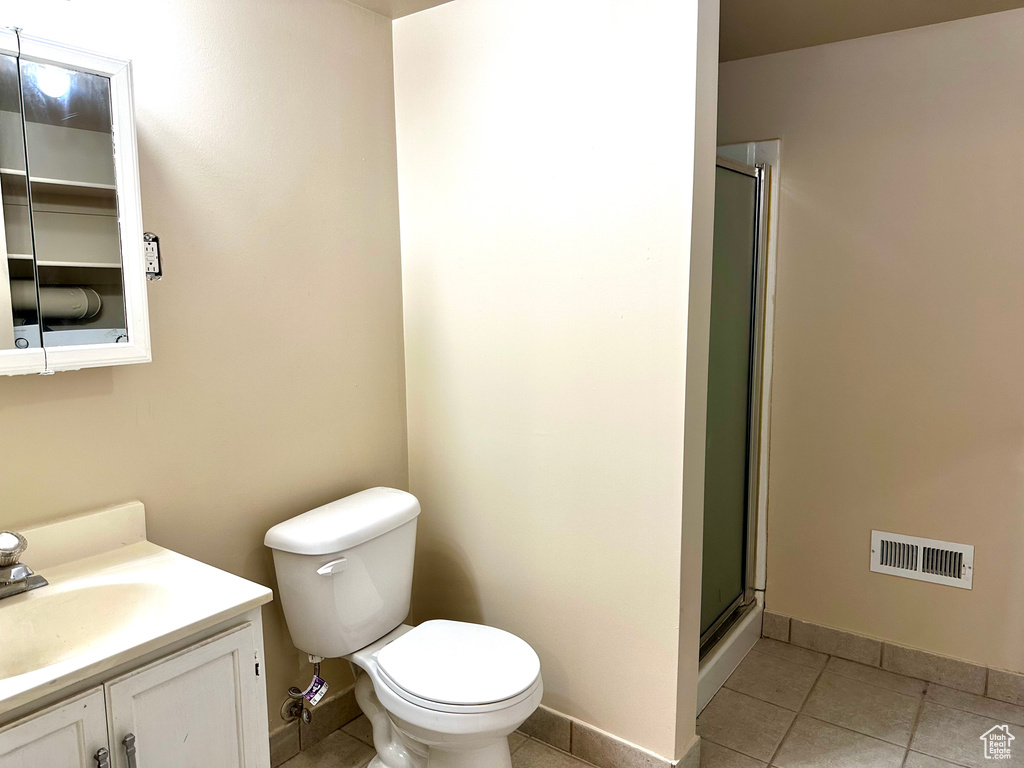 Bathroom with tile patterned floors, vanity, toilet, and an enclosed shower