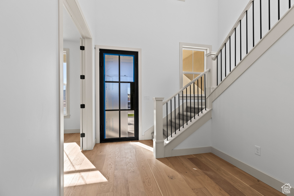 Foyer entrance with a towering ceiling and light hardwood / wood-style floors