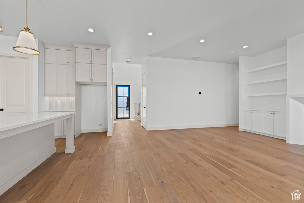 Unfurnished living room with light hardwood / wood-style floors and built in shelves