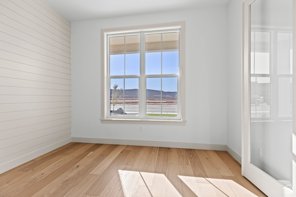 Unfurnished room featuring a mountain view, wooden walls, and light wood-type flooring