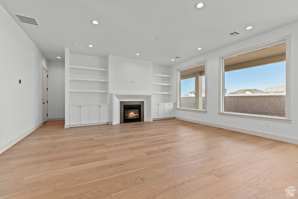 Unfurnished living room featuring built in features and light hardwood / wood-style flooring