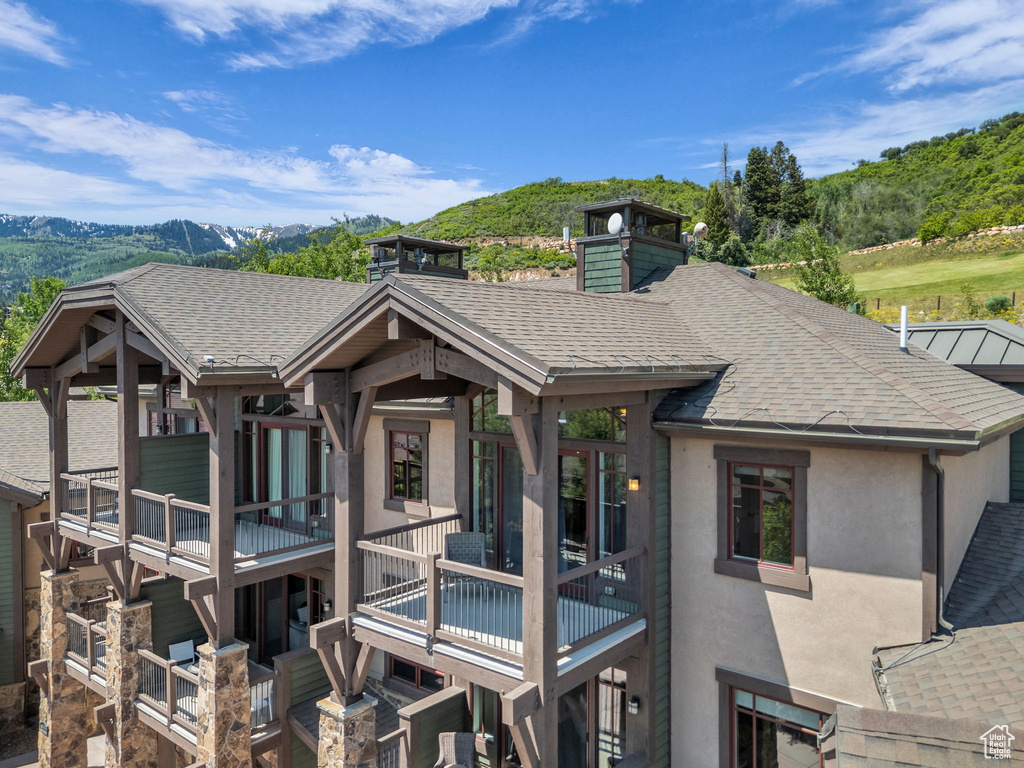 Rear view of property featuring stucco siding, a mountain view, and a shingled roof
