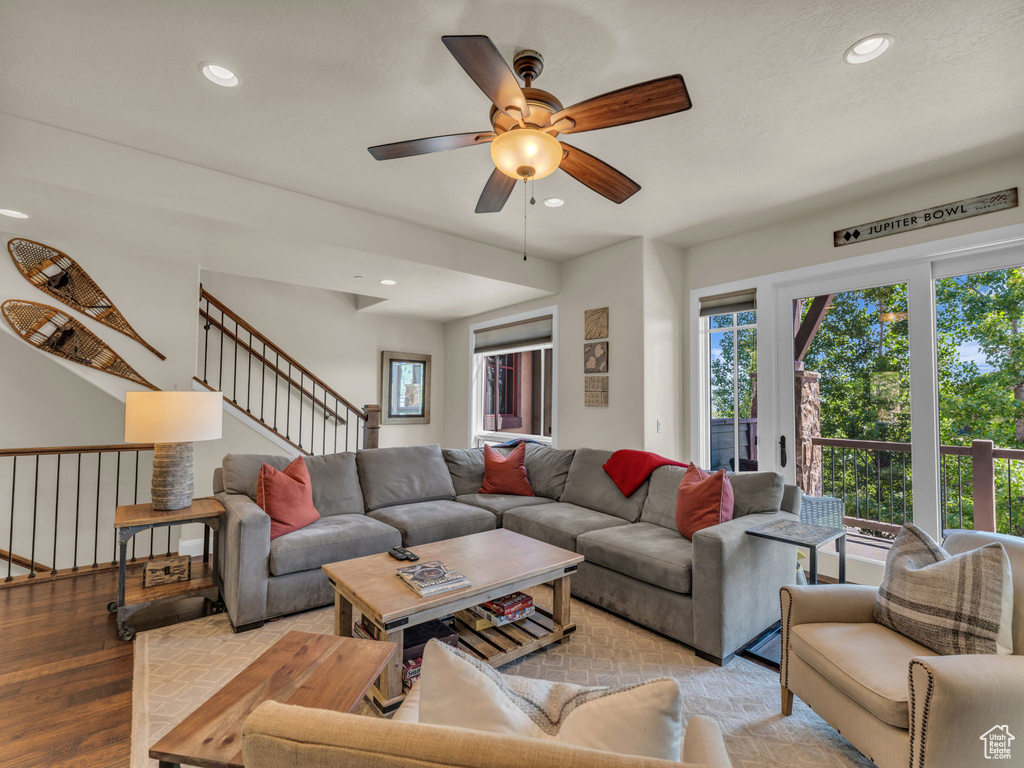 Living room with a ceiling fan, recessed lighting, plenty of natural light, wood finished floors, and stairway